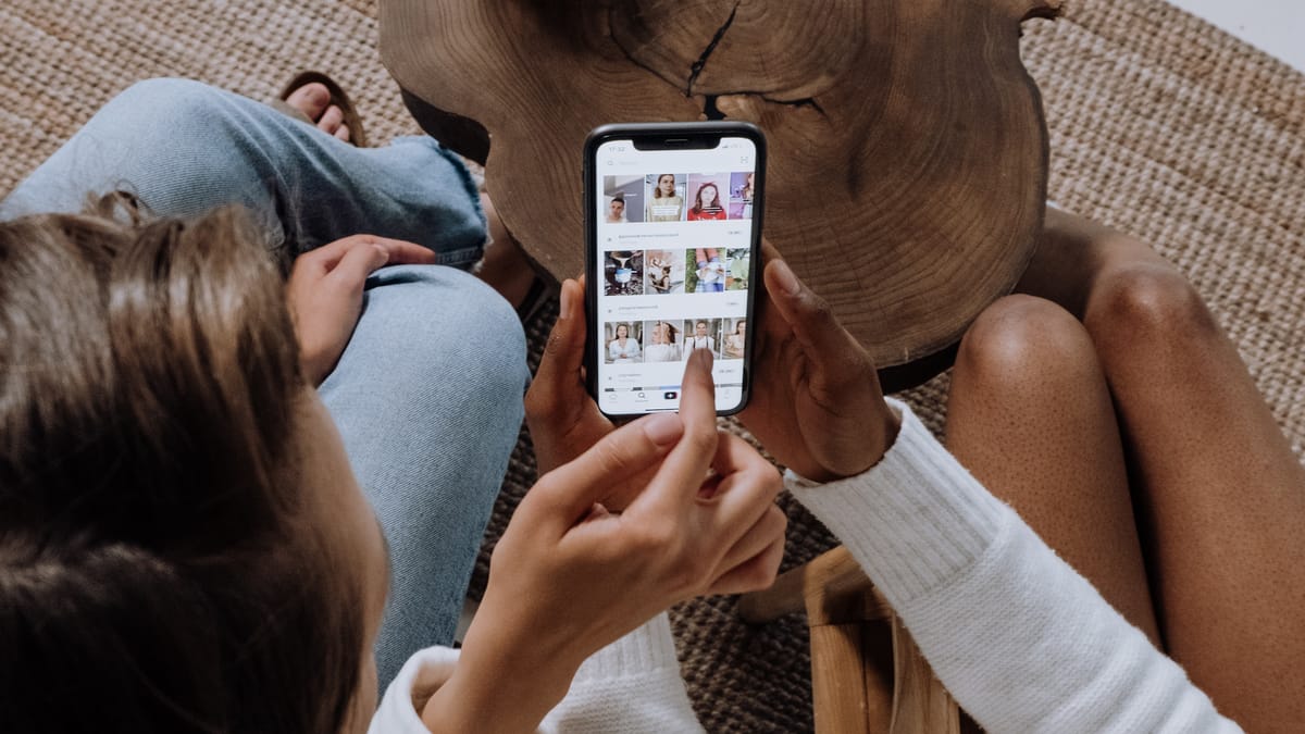 Two women sharing a smartphone screen to surf social media feeds