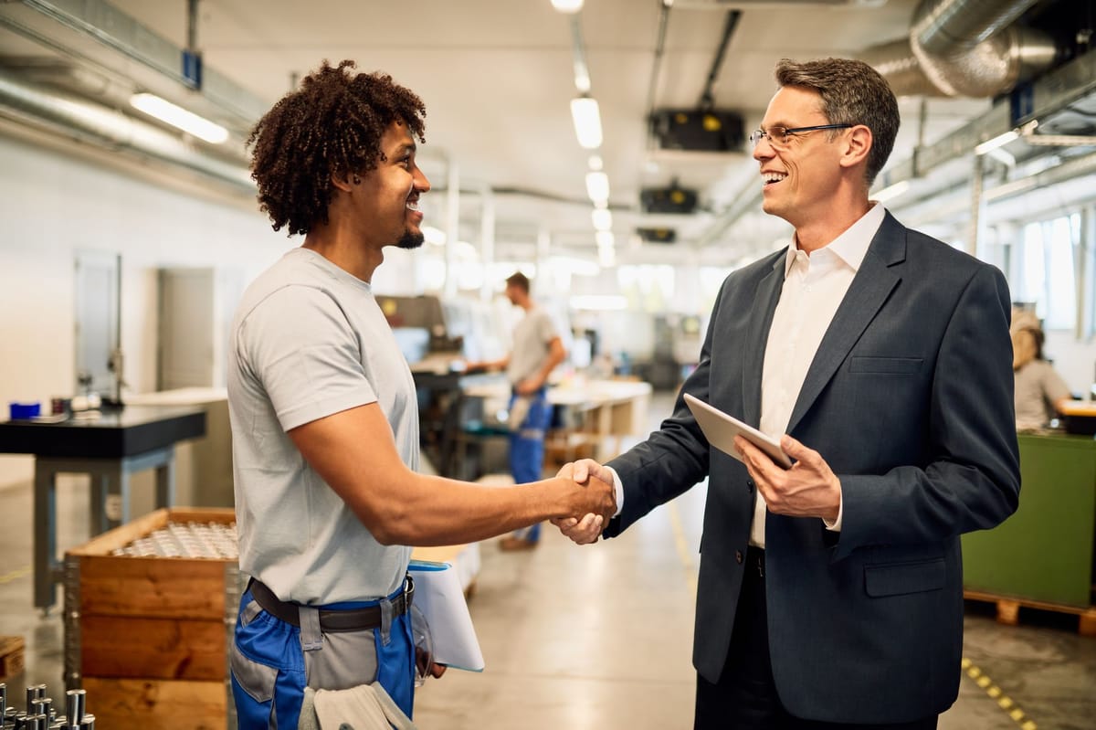 A satisfied buyer shaking hands with the production manager of supplier with smile