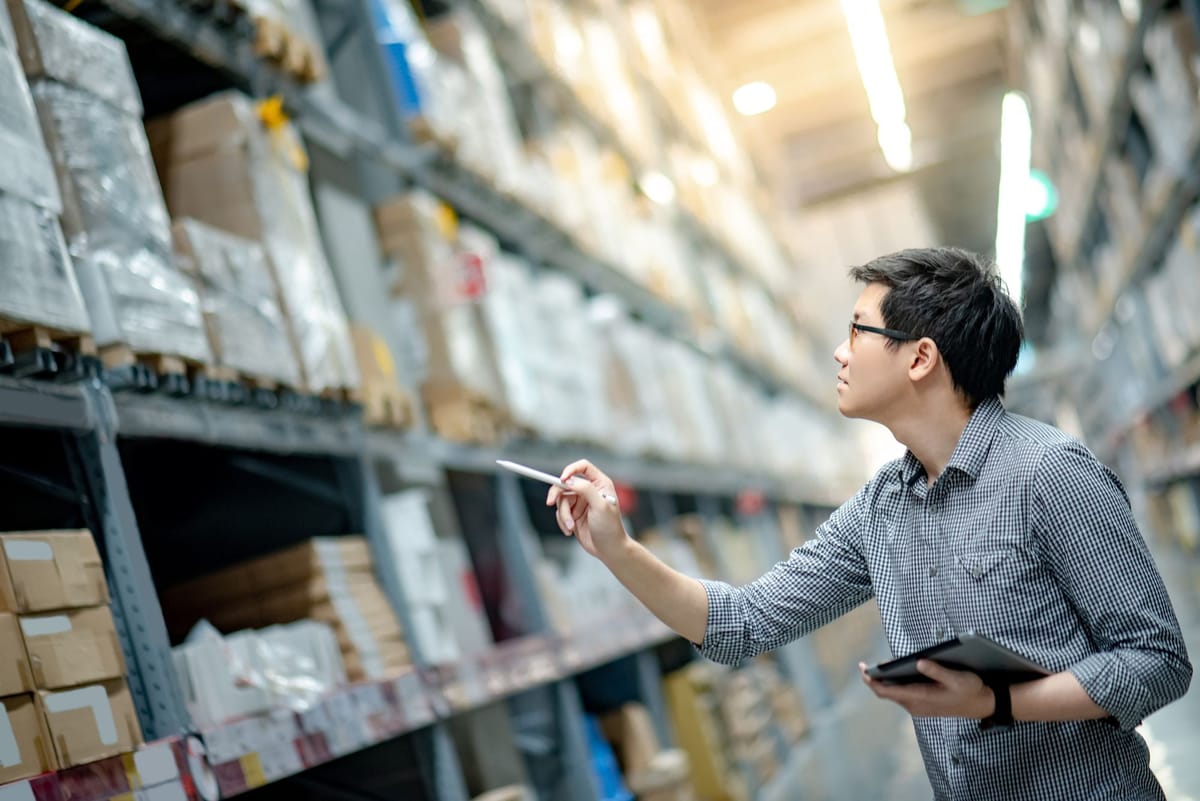 A man with a tablet PC looking at his inventory in a warehouse.