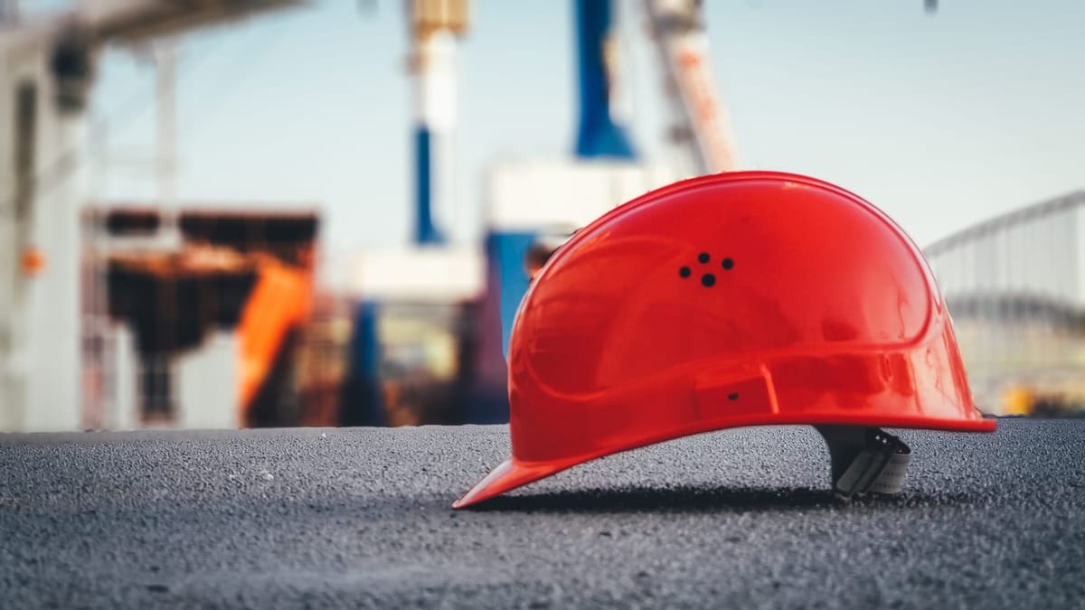 A red hardhat on a concrete road.