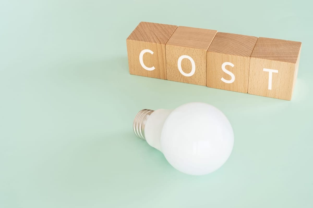 Wooden blocks with "COST" text of concept and a lightbulb.