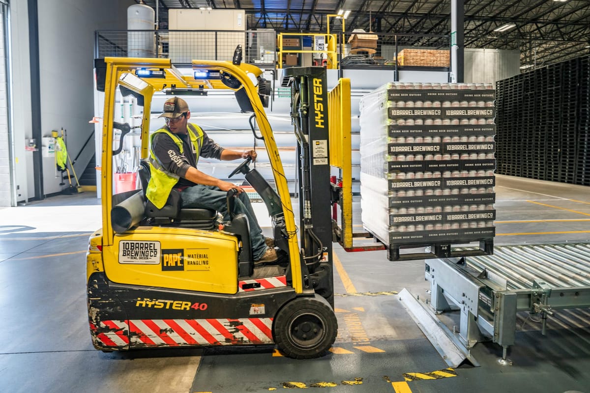 Warehouse operations: A forklift driver engaged in moving a pallet full of boxed products