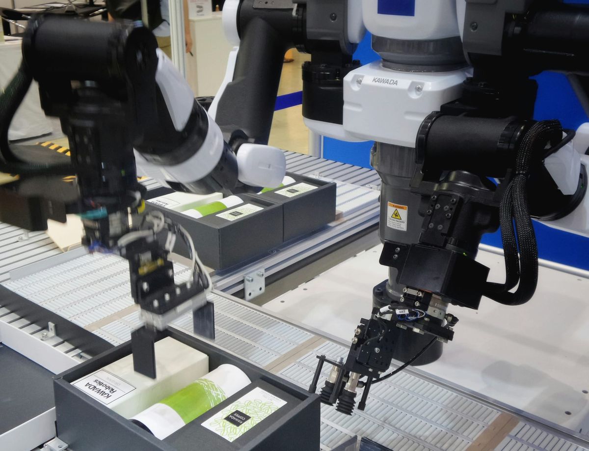 Robotic arms in a manufacturing process: A pair of robotic arms are engaged in an automated process, handling and placing items into boxes on a production line. 