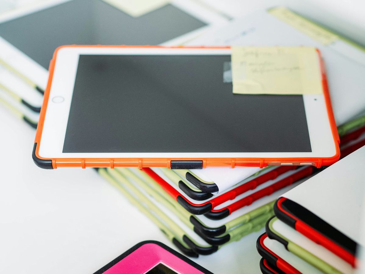 A stack of tablet devices on a white desk