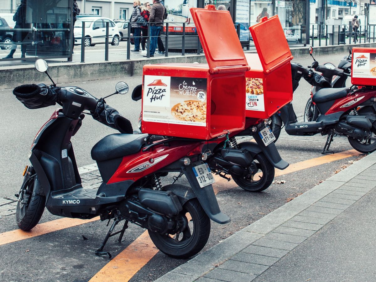 Pizza-Hut delivery motorcycles parked on the street waiting for the order