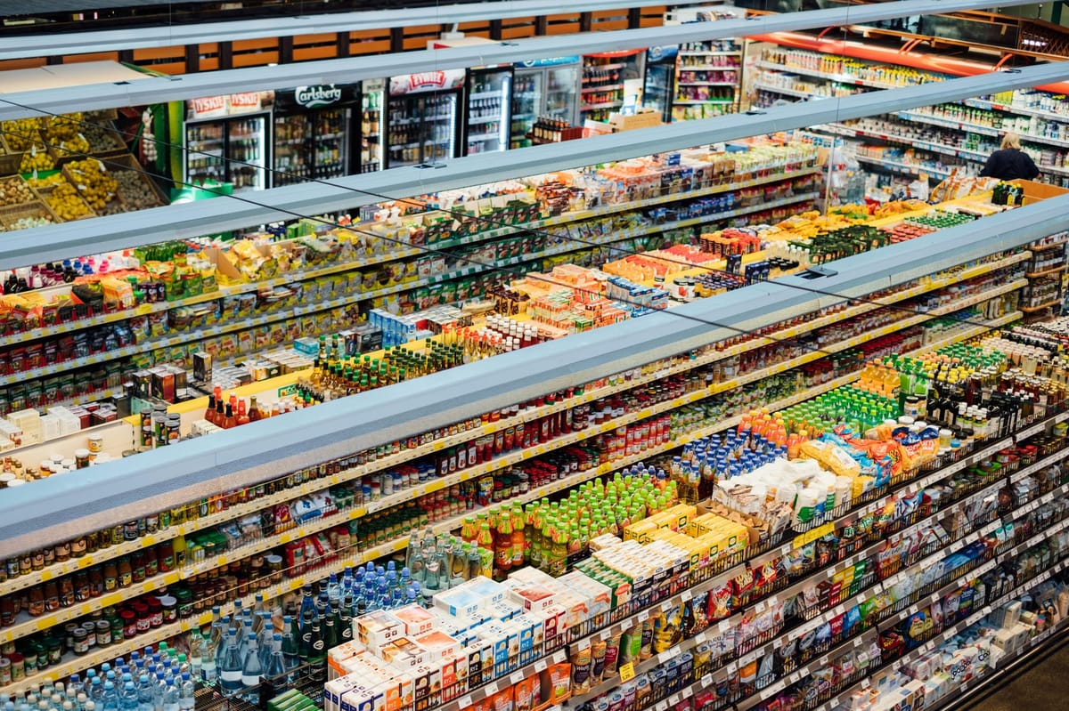 Wide view of fully stocked supermarket aisles showcasing packaged and shelf-stable food inventory.