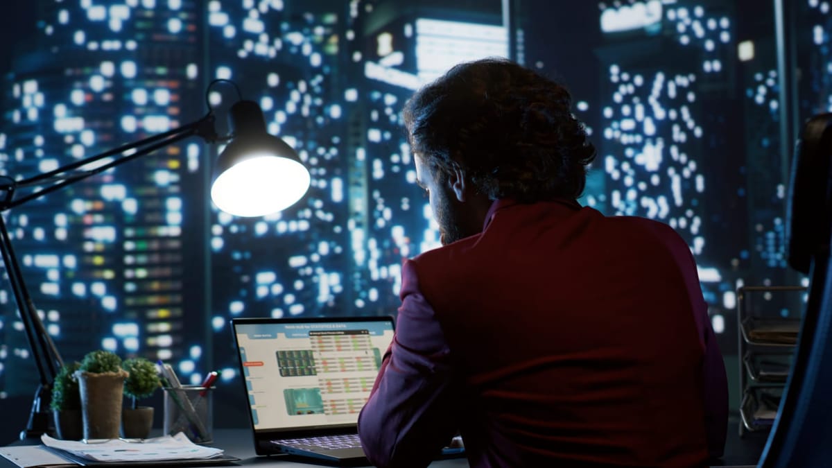 Business professional working late at night on a laptop with ransomware protection and data monitoring software displayed on the screen