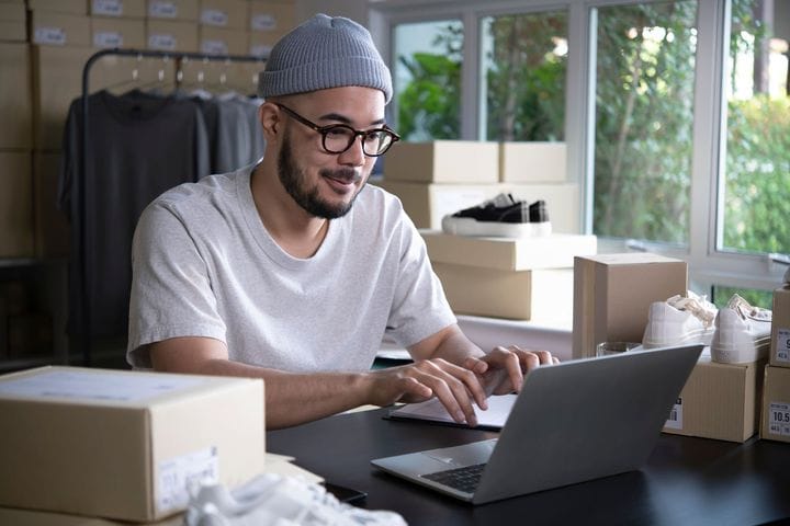 A male online shop owner forecasting demand on a laptop