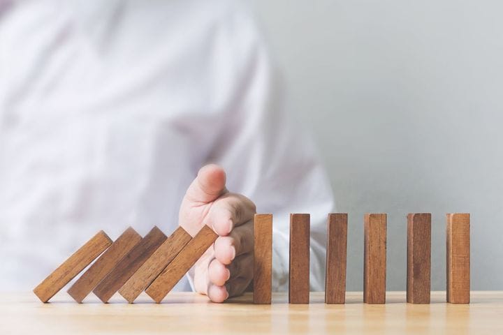 The executive stopping the falling dominoes with his own hands