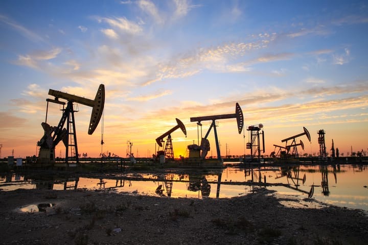 Oil field site, in the evening, oil pumps are running.