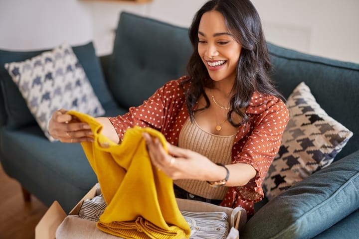 A happy shopper unboxing a personalized selection of apparel tailored to her preferences.