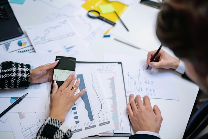 Hands of professionals analyzing printed financial charts and graphs during a business meeting.