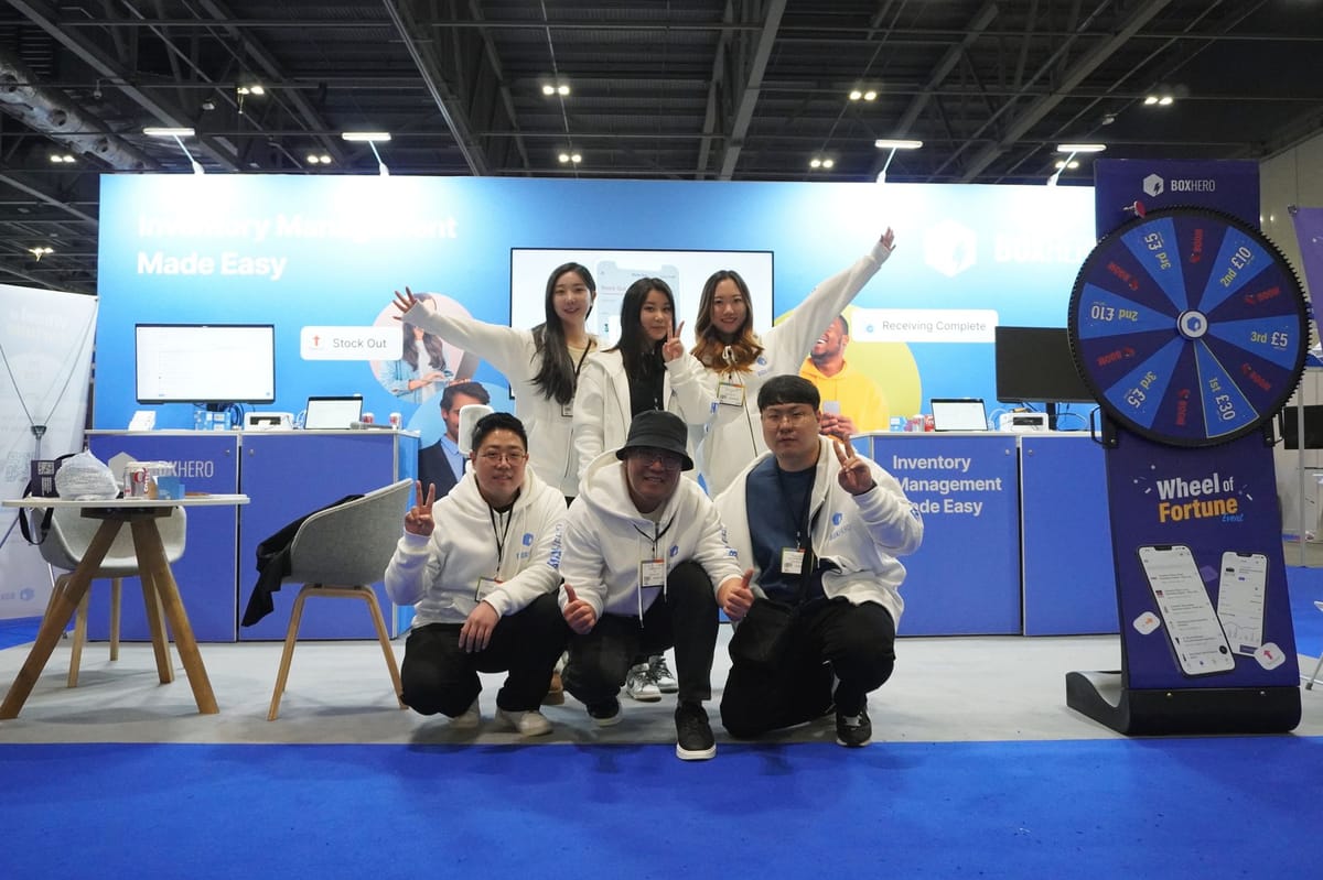 Miembros del equipo de BoxHero tomándose una foto con el stand de fondo