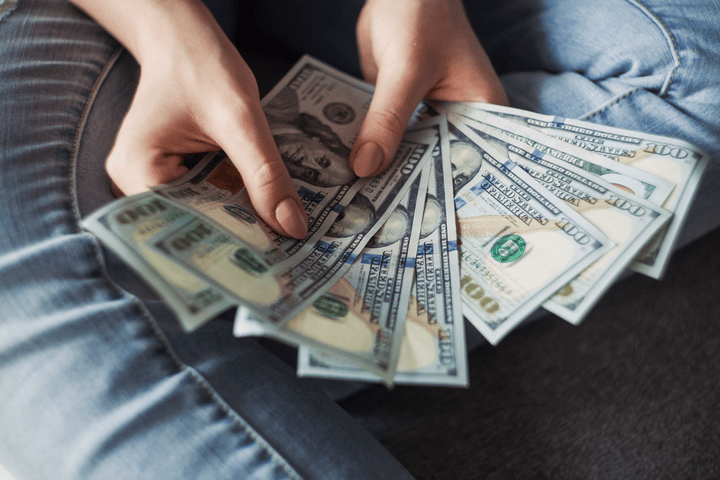 Chica sosteniendo billetes de dólar estadounidense.