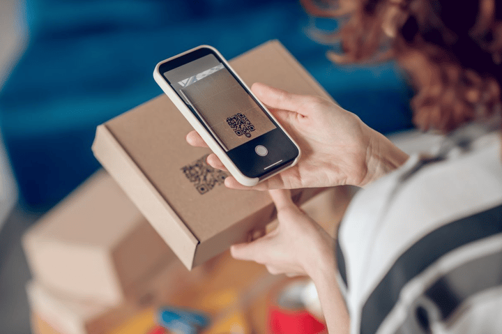 Persona escaneando un código QR en una caja con su smartphone.