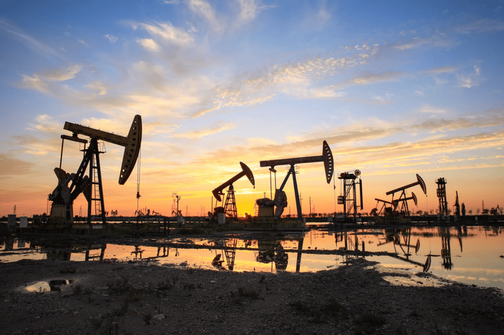 Campo petrolero al atardecer, con bombas de extracción en funcionamiento.