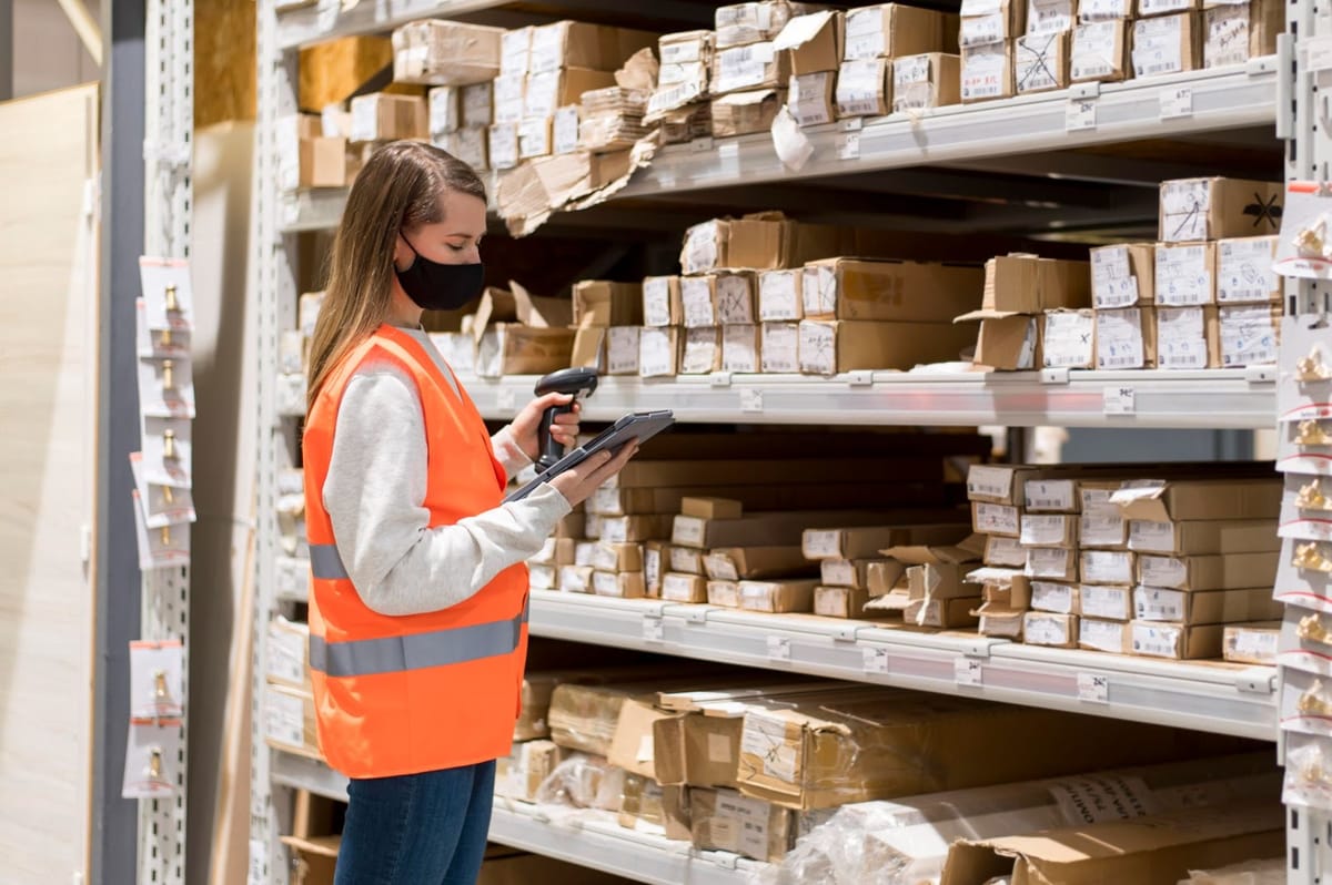 Woman organizing boxes in stockroom with barcode scanner and tablet