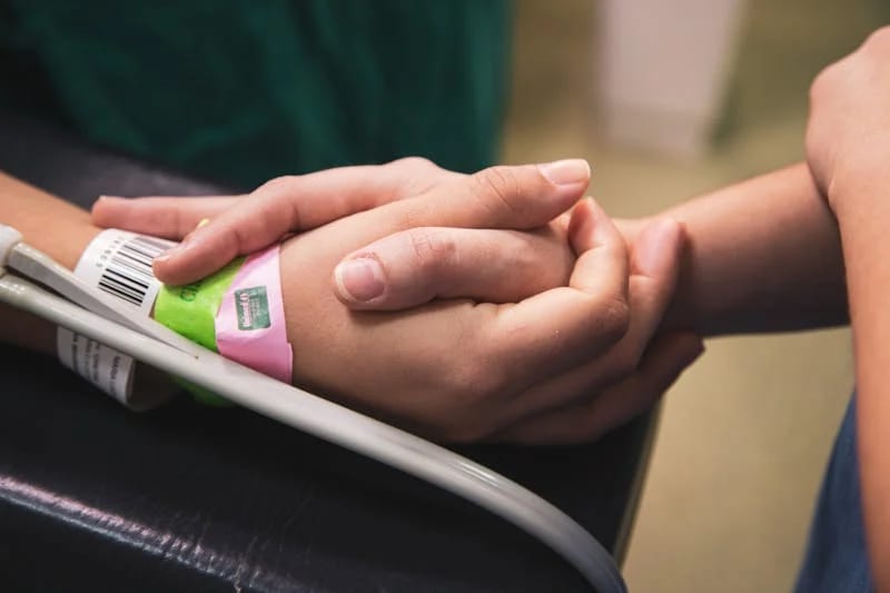 A patient with a barcode for tracking software holding hands with a loved one