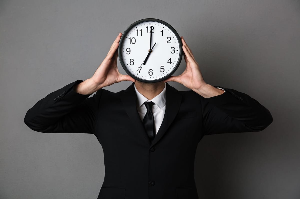 Man in suit holding a clock in front of his face