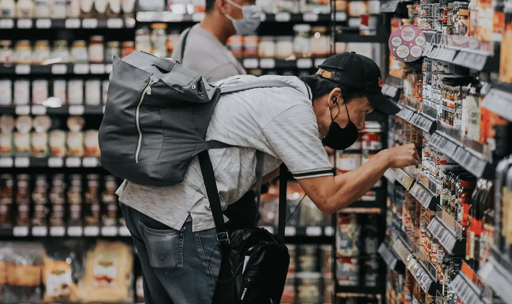 Dos hombres comprando en un supermercado, mirando las etiquetas