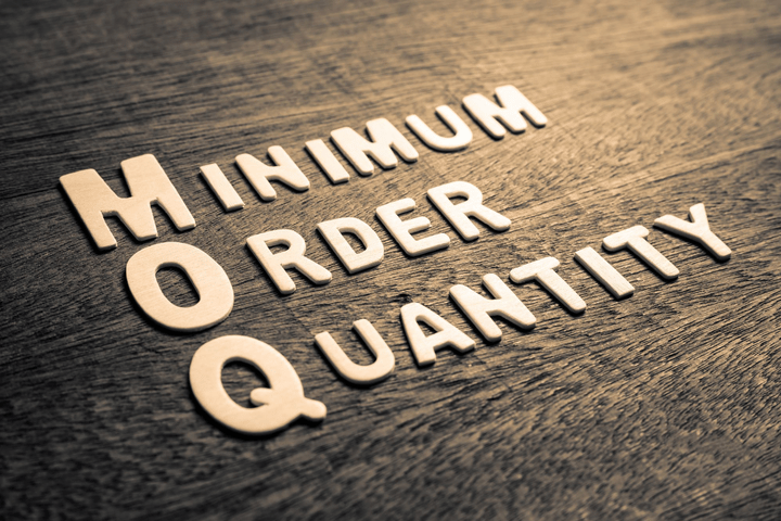 Señalizaciones de Cantidad Mínima de Pedido (MOQ) sobre un suelo de madera
