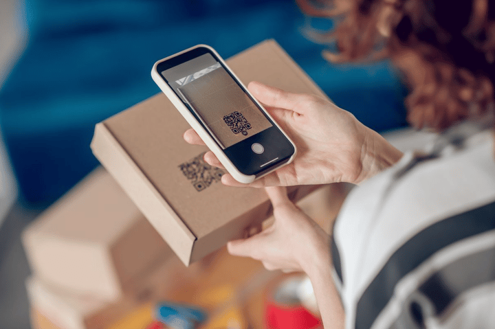 Persona escaneando un código QR en una caja con su smartphone.