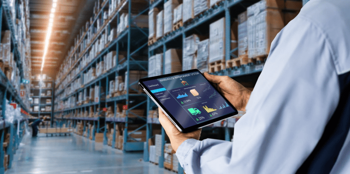 Gerente usando una tablet digital, mostrando el panel de control de software de gestión de almacenes con el fondo de un almacén desenfocado.