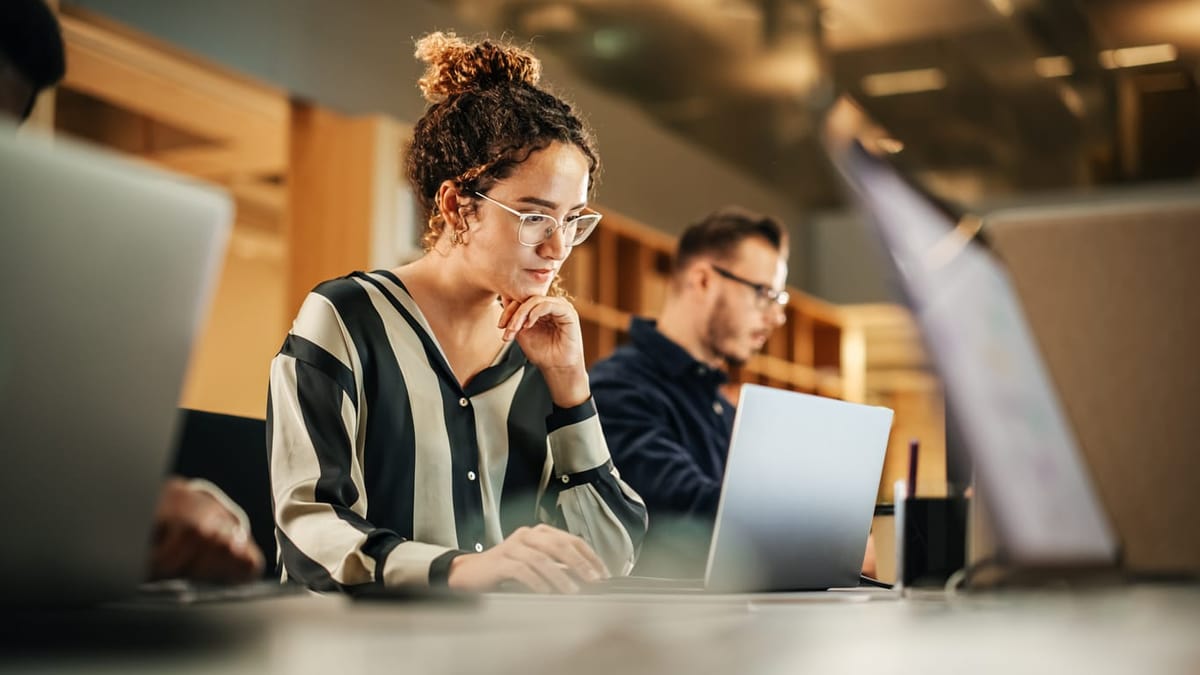 A woman in glasses staring at her laptop screen.