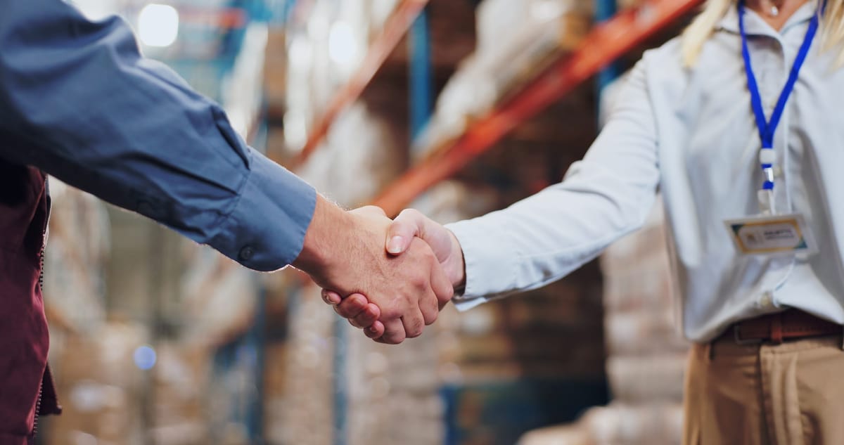 Handshake and agreement between two people in warehouse for supply chain partnership