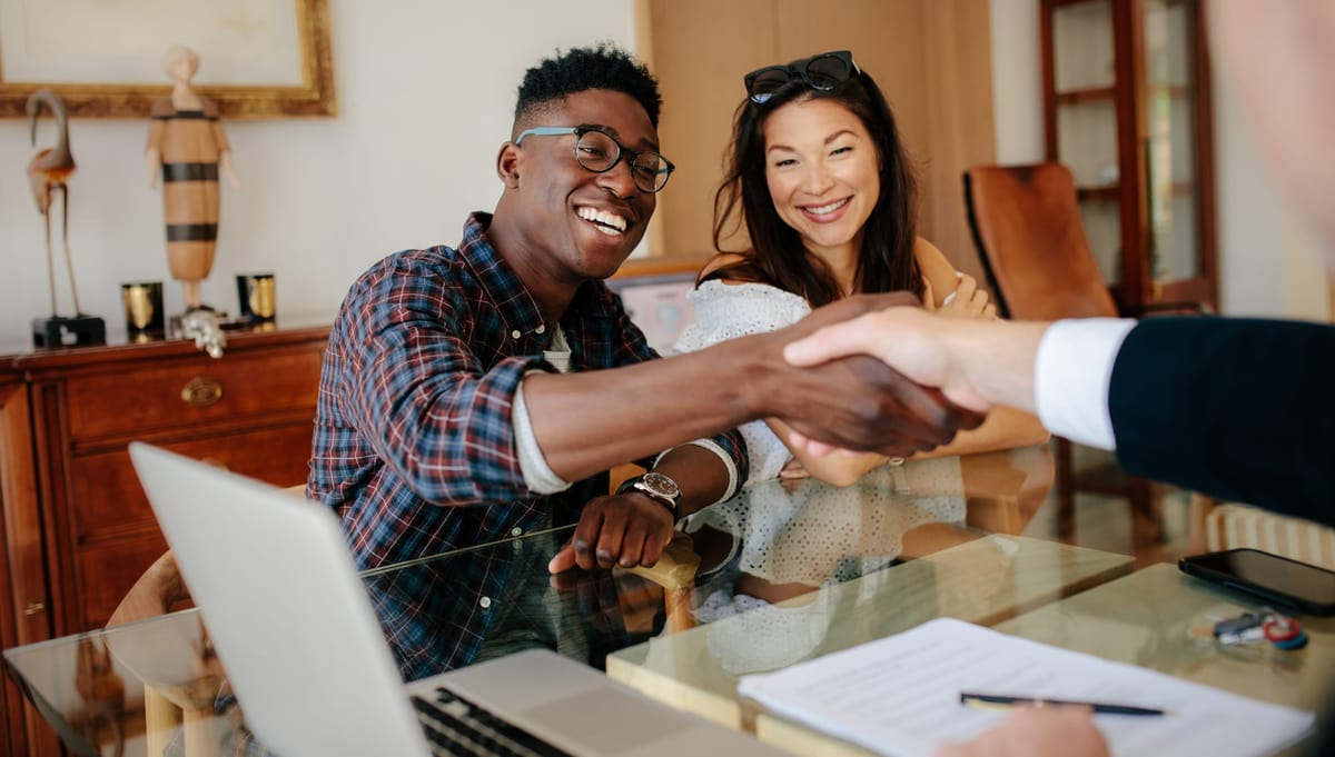 Happy couple shaking hands with a vendor after negotiating a deal