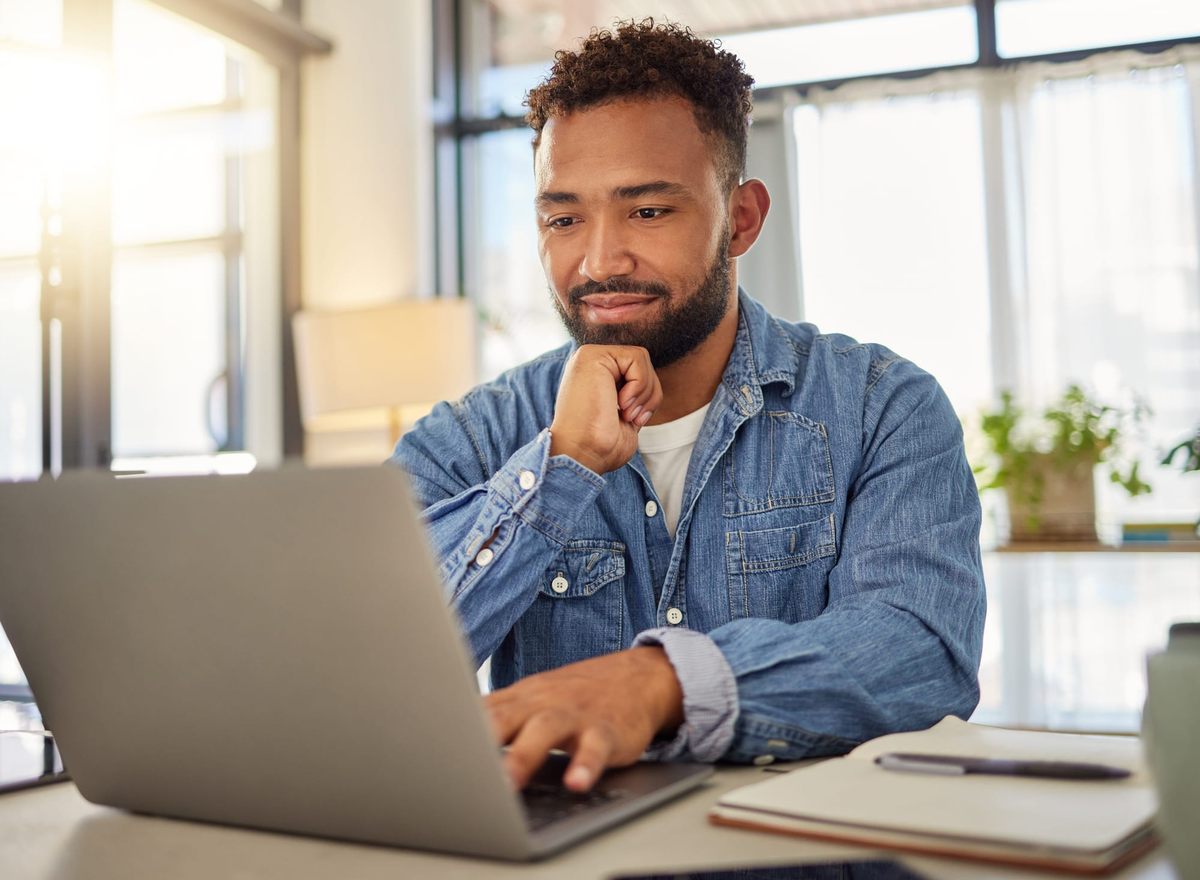 Happy businessman working on his laptop and thinking about inventory numbers