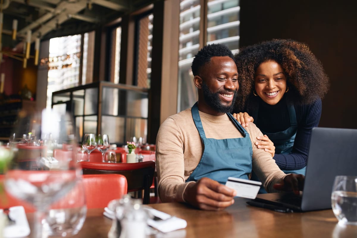 Restaurant owners using credit card online to pay bills on time and raise credit score