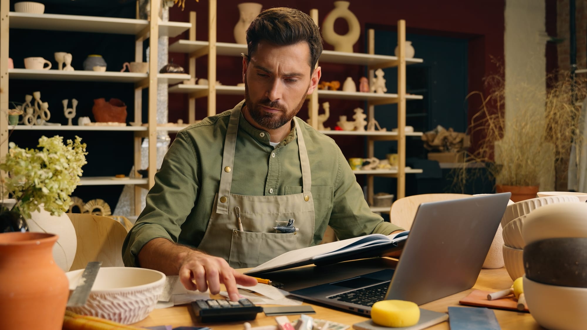 A small business owner businessman counting expense payment calculator taxes and working on laptop