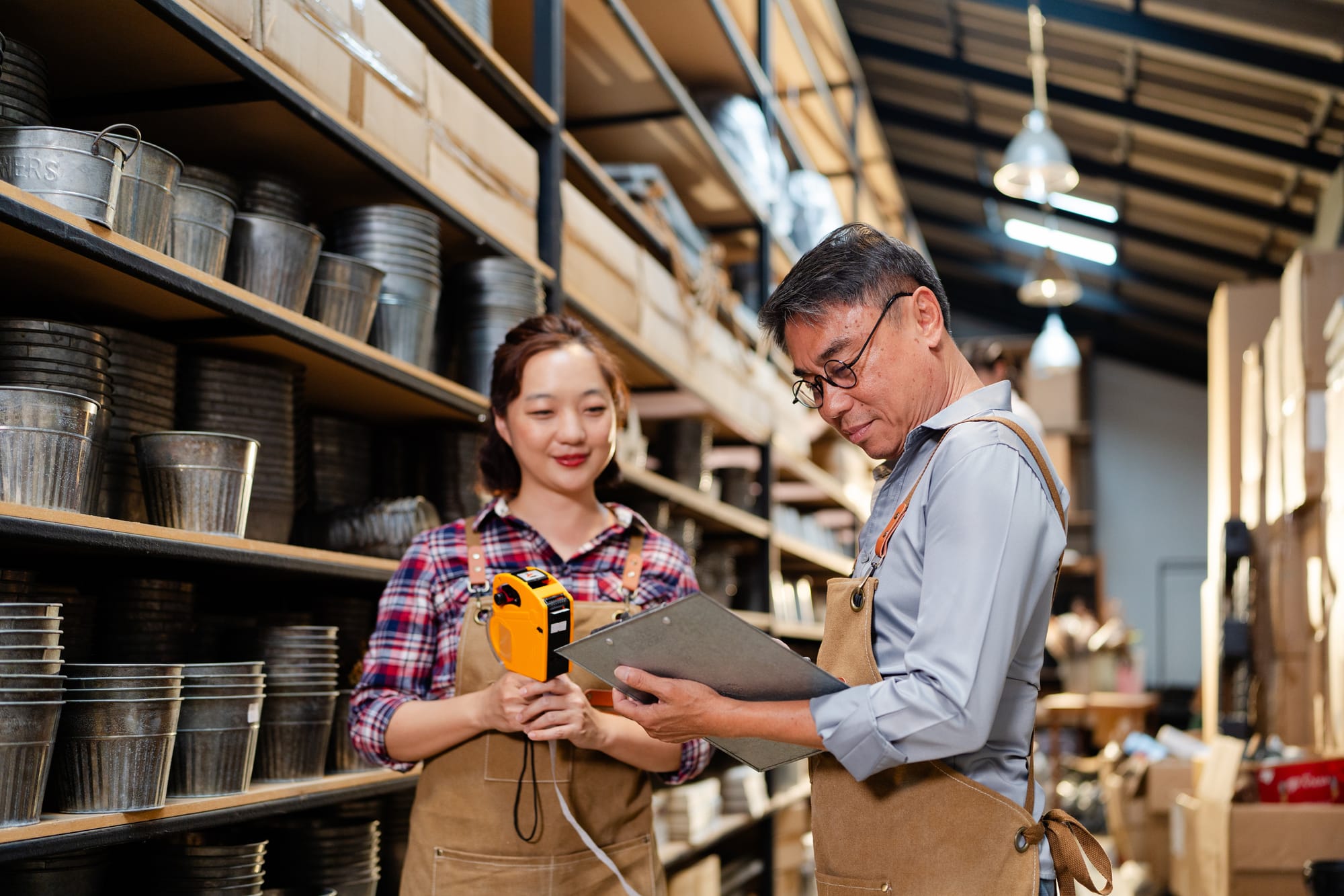 A team of Asian warehouse worker checking merchandise inventory count in store rac