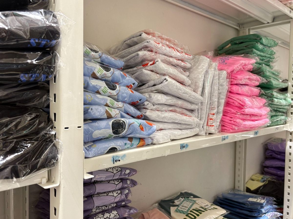 철제 선반에 포장된 의류들이 쌓여있다.